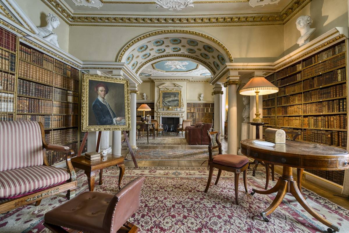 Biblioteca cálida con sillones, alfombra y estanterías, como una casa de los libros